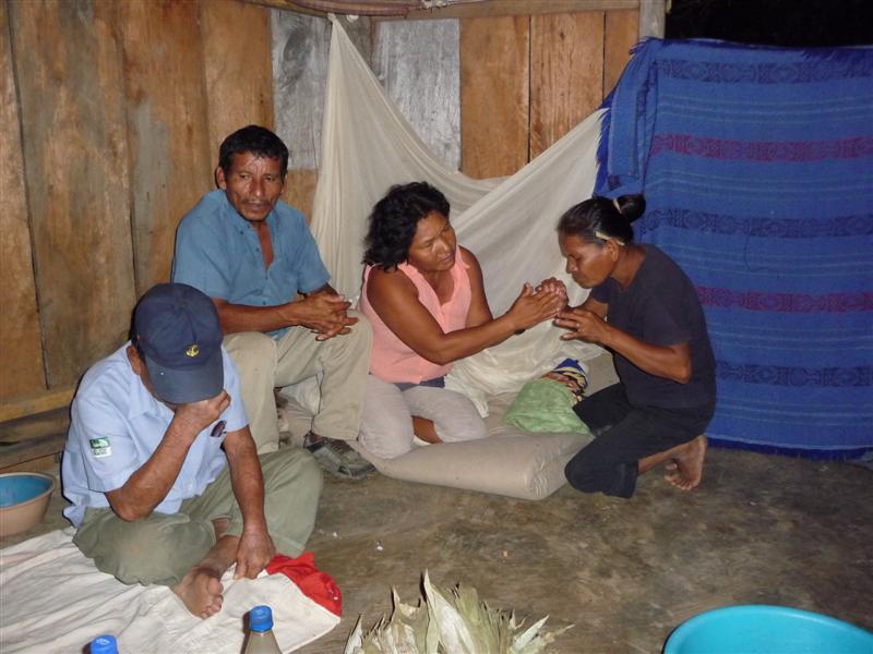 The shaman's wife blesses Manuel's wife's hands with smoke
